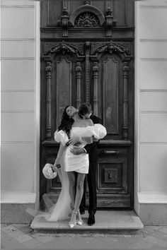 a man and woman standing in front of a wooden door