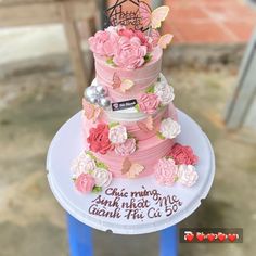 a three tiered cake with pink flowers and butterflies on the top is for someone's 50th birthday