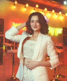 a woman in a white suit posing for the camera with her hands on her head