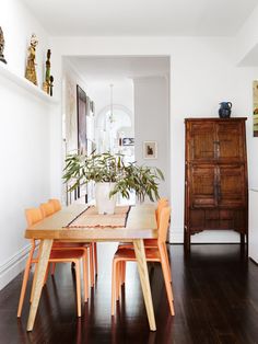 a dining room table with four chairs and a potted plant in the corner next to it