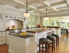 a large kitchen with an island in the middle and four stools at the counter