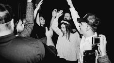 a group of people standing around each other with their hands in the air and one person taking a photo