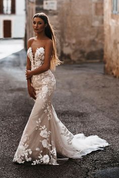 a woman in a wedding dress standing on the street