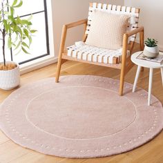 a living room with a chair and rug on the wooden floor next to a potted plant