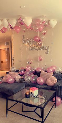 a living room filled with balloons and pink couches next to a coffee table on top of a carpeted floor