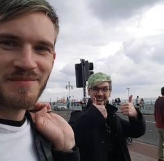 two men standing next to each other on a bridge with traffic lights in the background