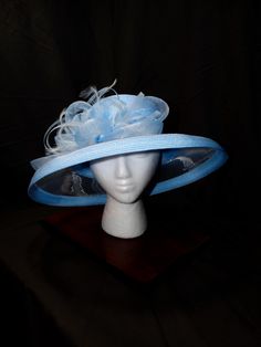 Sky Blue Symphony Derby Hat - Serene, Harmonious, Elegant This elegant derby hat is a perfect blend of femininity and sophistication. Its soft sky blue hue and intricate design create a captivating look. Sky Blue Color: A serene and calming color that adds a touch of elegance. Intricate Design: A beautiful, eye-catching piece with delicate details. Premium Materials: Crafted with high-quality materials for durability and comfort. Versatile Styling: Can be worn in various ways to suit your style. Make a Statement Today! Elevate your style with this unique accessory--shop now and turn heads at your next event! Elegant Blue Fedora With Short Brim, Blue Adjustable Fedora For Kentucky Derby, Blue Curved Brim Headpiece For Royal Ascot, Blue Brimmed Fascinator For Spring, Brimmed Blue Fascinator For Spring, Blue Fascinator With Curved Brim For Spring, Blue Curved Brim Fascinator For Spring, Blue Fitted Fedora With Flat Brim, Blue Fascinator For Kentucky Derby Garden Party