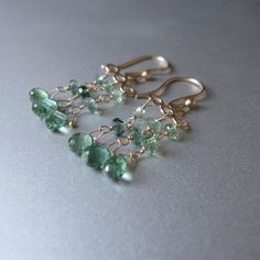 Soldered and hammered gold loops suspend columns of faceted rondelles and briolettes, cascading in shades of blue-green tourmaline. The gold earwires and loops has been given a satin finish. The earrings hang 1 1/2" total. To see more tourmaline earrings: https://www.etsy.com/shop/jenco8?ref=seller-platform-mcnav&search_query=tourmaline+earrings Check out Jenco Studios at: www.jencostudio.com and www.facebook.com/jencostudios for work in sterling silver, new work previews, info on upcoming sales Elegant Wire-wrapped Tourmaline Jewelry, Elegant Wire Wrapped Tourmaline Jewelry, Elegant Tourmaline Wire Wrapped Jewelry, Elegant Dangle Tourmaline Jewelry, Elegant Tourmaline Teardrop Earrings, Elegant Tourmaline Dangle Earrings, Elegant Green Tourmaline Earrings, Green Chandelier, Green Chandeliers