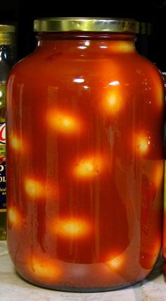 an orange jar sitting on top of a counter next to jars with liquid in them