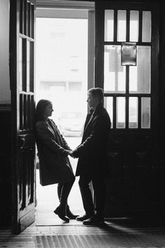 black and white photograph of two people shaking hands in front of an open door,