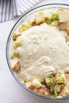 a glass bowl filled with potato salad and dressing