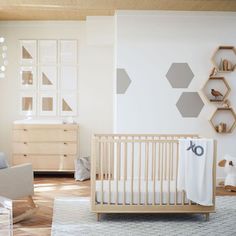 a baby's room with wooden furniture and hexagonal wall art on the walls