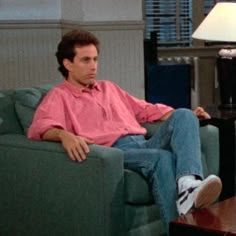 a man sitting in a chair with his feet on the coffee table next to him