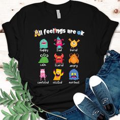 Embrace every emotion in the classroom with our "All Feelings Are OK" t-shirt, designed especially for teachers. This vibrant and playful design features nine adorable and colorful monsters, each showcasing a different, expressive face. Perfect for creating a supportive and encouraging environment, this t-shirt reminds students that all feelings are valid and worth celebrating. Made from soft, high-quality fabric, it's an excellent way for teachers to show their students that it's okay to feel however they feel and that every emotion has its place in learning and growing. We guarantee 100% customer satisfaction and high quality products! 𝗛𝗢𝗪 𝗧𝗢 𝗢𝗥𝗗𝗘𝗥? 𝟏. Select the shirt 𝗦𝘁𝘆𝗹𝗲 2. Select the 𝗦𝗶𝘇𝗲 3. Select the shirt color 4. Select the quantity, 5. Click 𝗔𝗗𝗗 𝗧𝗢 𝗖𝗔 Playful Character Print T-shirt With Relaxed Fit, Funny Short Sleeve Shirt With Character Print, Black Novelty Shirt With Graphic Print, Black Relaxed Fit Funny Tops, Novelty Multicolor Tops With Character Print, Novelty Black T-shirt With Character Print, Funny Cartoon Print Relaxed Fit T-shirt, Fun Relaxed Fit Shirt With Character Print, Funny Multicolor Shirt With Character Print