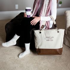 PREMIUM QUALITY: Large tote bag with metal feet comes packaged in a plastic polybag, is made from canvas and vegan leather, and features two rope handles and both zipper and snap closures. IN-HOUSE DESIGN: "Mom Life Is The Best Life" text and lotus flower icon are both sewn into the front of the bag. BAG DETAILS: Interior of the bag features three pockets: two open and one zipper. CARE INSTRUCTIONS: Wipe clean with a damp cloth.