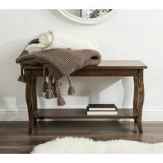 a wooden bench with a blanket on top of it next to a book and a mirror