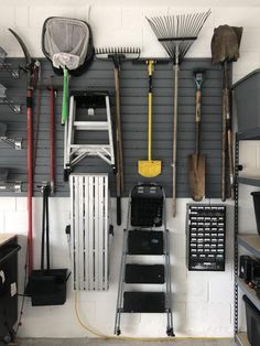 a garage with various tools hanging on the wall, including brooms and rakes