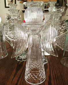 a glass candle holder sitting on top of a wooden table next to other glass candles