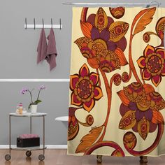 a shower curtain with an orange and red flower design on it next to a bath tub