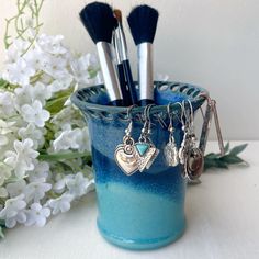 a cup filled with makeup brushes next to white flowers