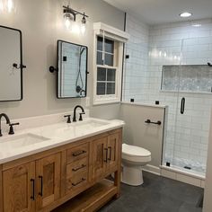 a bathroom with two sinks, a toilet and a walk in shower