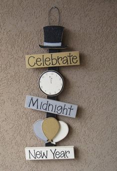 a clock and some signs hanging on the side of a wall that says celebrate midnight, new year