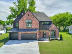 a large brick house in the middle of a grassy area with trees and bushes around it