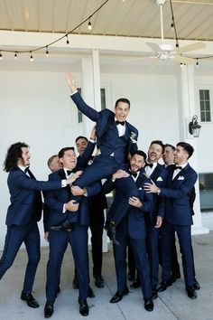 a group of men in tuxedos are posing for a photo with each other