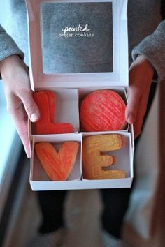 a person holding an open box with some fruit in it and the word love spelled out