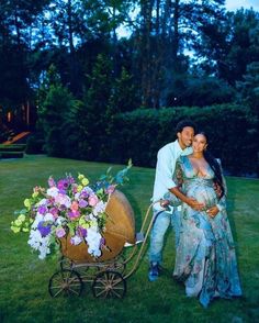 a man and woman are posing for a photo with a baby carriage in the grass