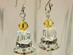 a pair of earrings with yellow and clear crystal stones on it's earwires