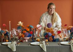 a woman sitting at a table with flowers and candles