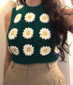 a close up of a person wearing a green sweater with white flowers on the front