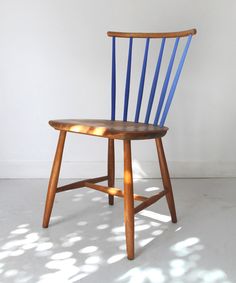 a wooden chair with blue paint on it's seat and back, in front of a white wall