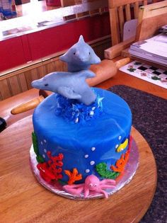 a blue cake with an ocean theme on it and a dolphin figurine sitting on top