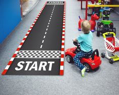 a young boy riding a toy car on top of a race track