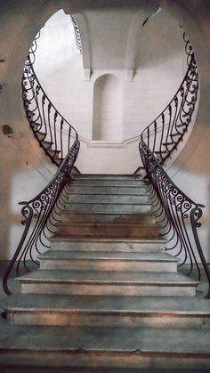 a set of stairs with wrought iron railings leading up to an arched doorway in a building