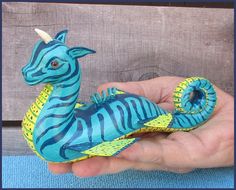 a hand holding a small blue and yellow zebra figurine