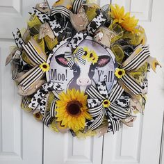 a wreath with sunflowers and cow faces on it is hanging on the front door