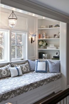 a window seat with pillows on it next to a bookshelf