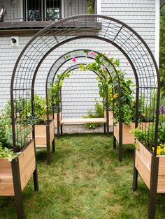 an outdoor garden with several wooden planters and metal trelliss on the grass