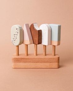 four wooden pegs with different shapes and colors on them, sitting in front of a pink background