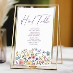 a close up of a sign on a table with flowers in the background and text that reads, head table