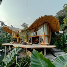 an unusual house in the middle of some tropical plants and trees, surrounded by greenery