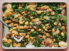 a pan filled with spinach and chickpeas covered in seasoning next to lemon wedges