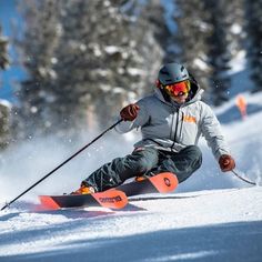 a man riding skis down the side of a snow covered slope with trees in the background