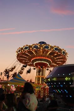 people at an amusement park with rides and carousels in the background during sunset or dawn