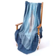 a chair with a blanket on top of it and a wooden arm rest in front of the chair