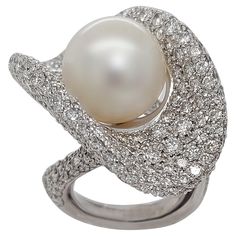 Magnificent 18kt white gold ring with diamonds and a big South Sea 14.3 mm pearl Diamonds: 350 brilliant cut diamonds, Total : Ca. 14.50 Carat of Top color and clarity diamonds. Pearl: South Sea 14.3 mm Material: 18kt solid white gold Total weight: 40.5 gram / 1.425 oz / 26.0 oz Ring size: This ring has a ring adjuster so it can go up to size 55 and makes the ring extra comfortable to wear.(can be resized for free) Measurements head of ring: Length 24 mm x Width 36.2 mm, Measurements whole ring: Ring Adjuster, White Pearl Ring, Pearl And Diamond Ring, Big Pearl, Pave Diamond Ring, Ring Fit, Pearl Diamond, White Gold Ring, Quality Diamonds