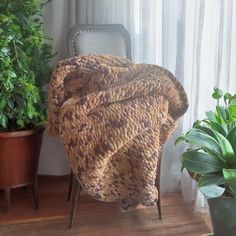 a chair with a blanket on it next to a potted plant